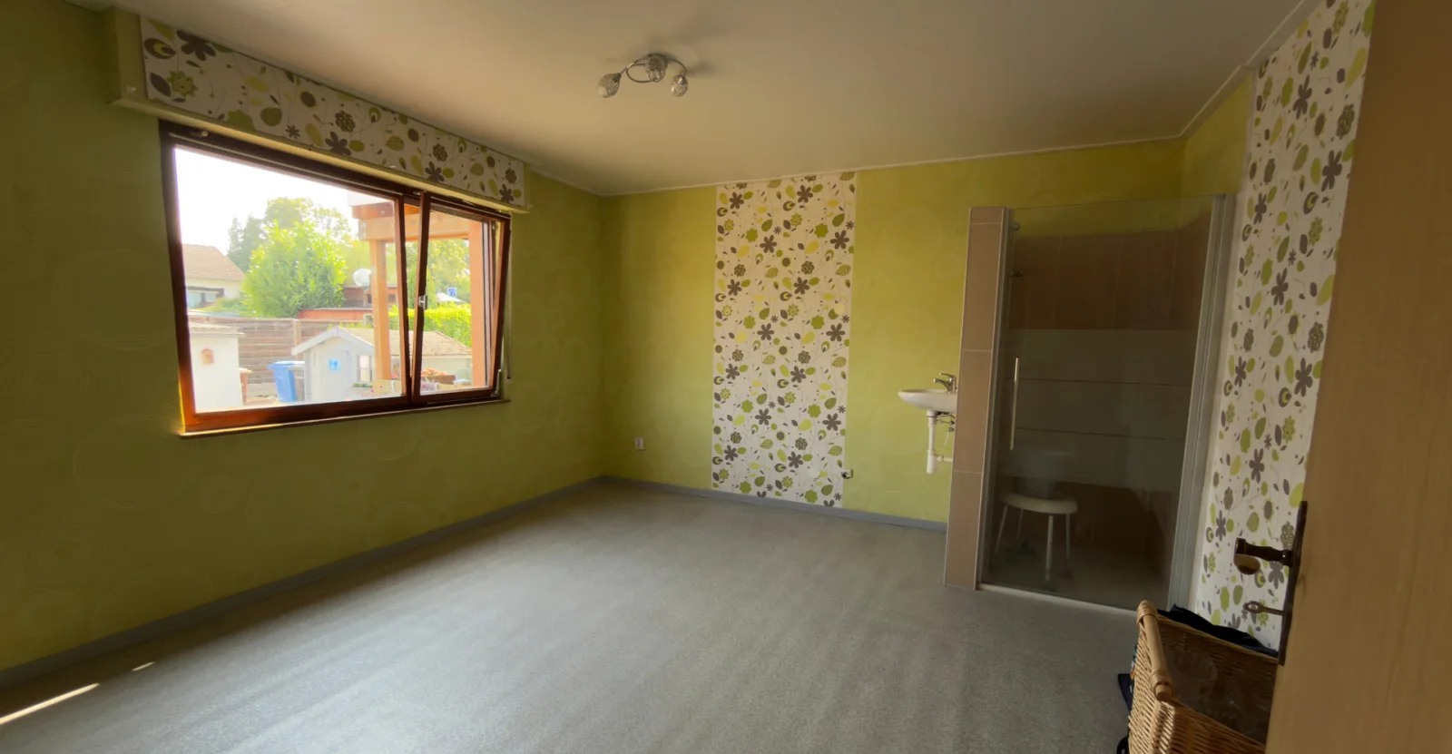 Vorher: Wohnzimmer mit gemusterter Tapete und Teppichboden in einem Sanierungsobjekt in Stuttgart vor der virtuellen Sanierung.